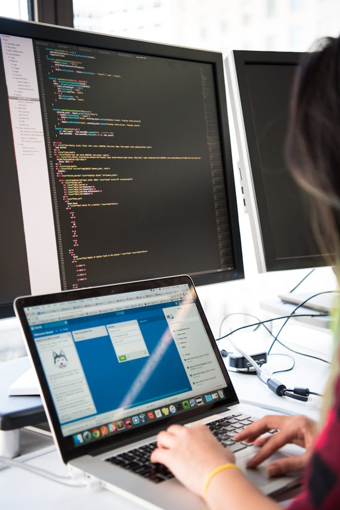 about-01 Programmer working on code across multiple screens in a modern office setting.