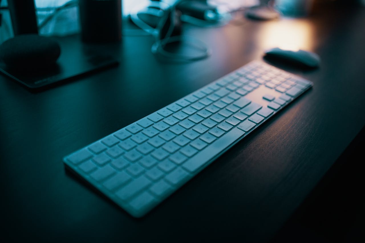 ours-journey A modern wireless keyboard placed on a sleek desk, illuminated by ambient lighting in a tech-savvy office setting.