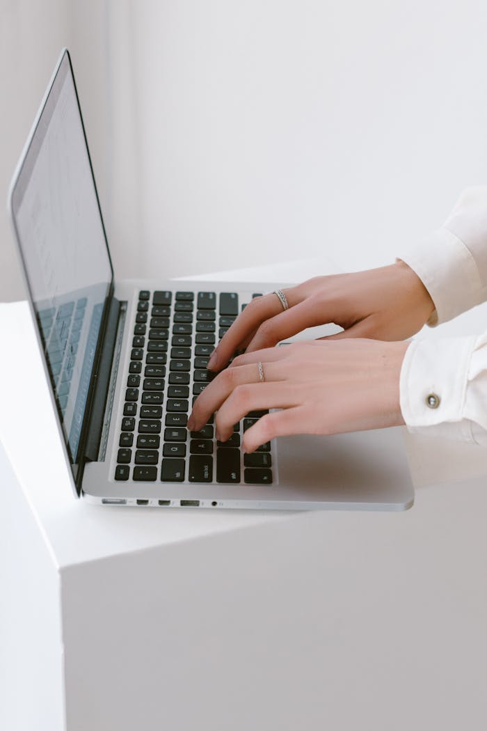 our-services-1 Close-up of hands typing on a laptop in a bright, minimalist indoor setting.